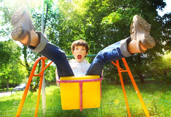 Préadolescent beau garçon balançant sur la balançoire en été journée ensoleillée — Photo