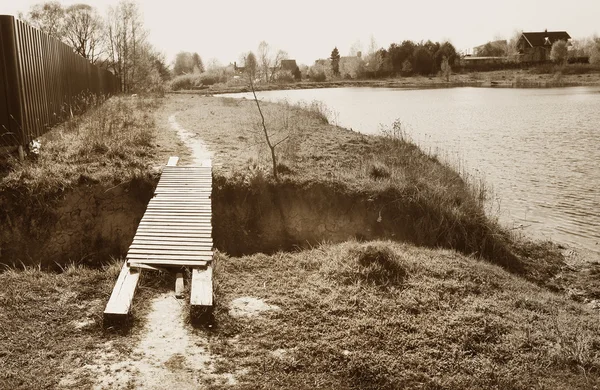 Monokrom gammalt foto av byn dammen och träbro — Stockfoto