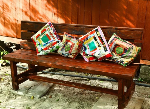 Beautiful patch work pillows on the wooden bench — Stockfoto