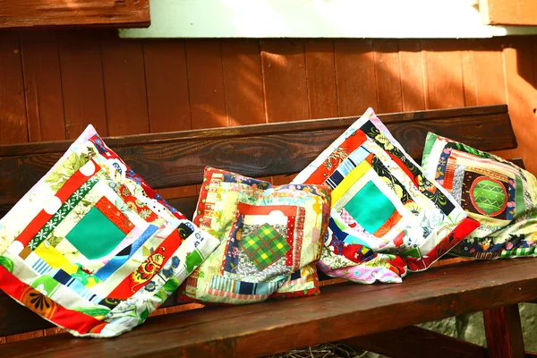 Beautiful patch work pillows on the wooden bench — Stockfoto