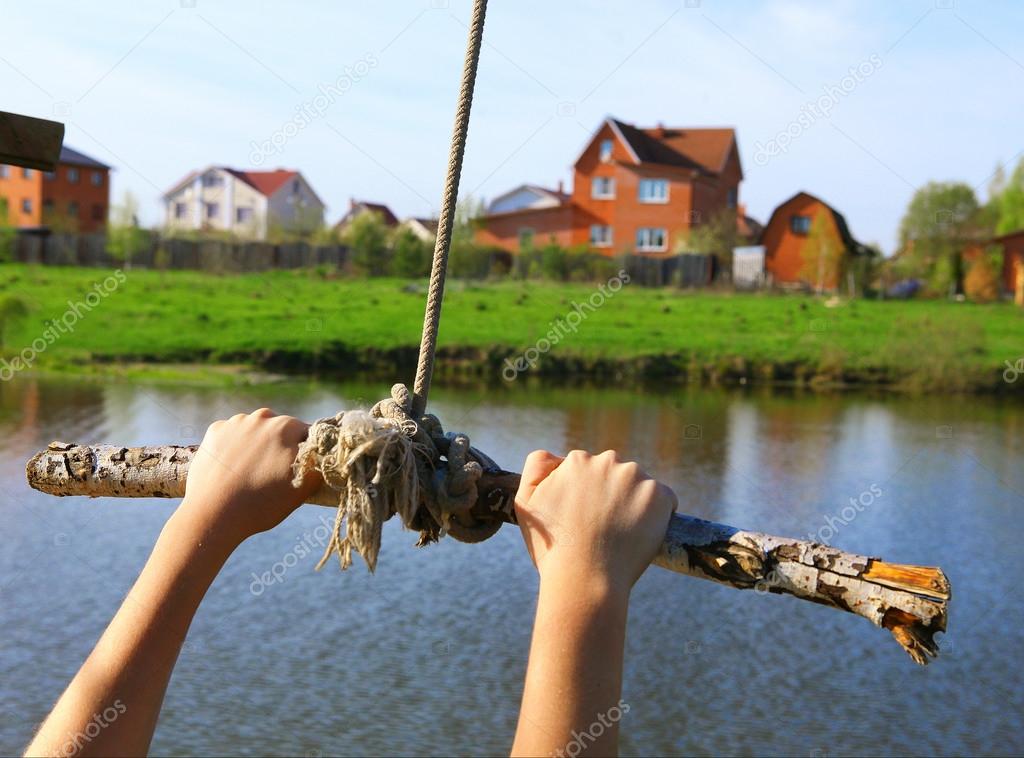 Hands hold rope swing before jump into the water on the lake and — Stock  Photo © Ulianna #75200653