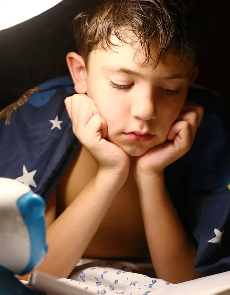 Preteen schöner Junge las Buch mit Lampe vor dem Schlafen — Stockfoto