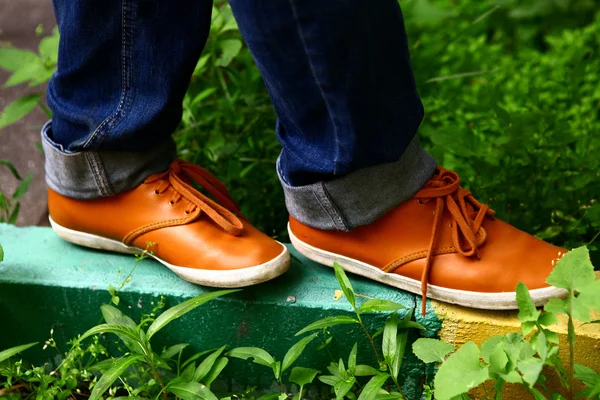 Fötter med orange bekväma skor gå på gränsa i staden gatan — Stockfoto