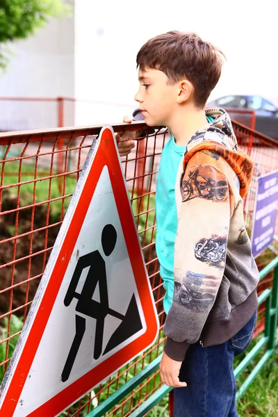 Frühreifer gutaussehender Junge an der Baugrenze mit Warnsignal — Stockfoto