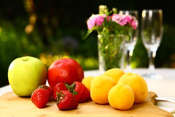 Fruit diversiteit op de houten bord met wijn glazen en wild anjer — Stockfoto