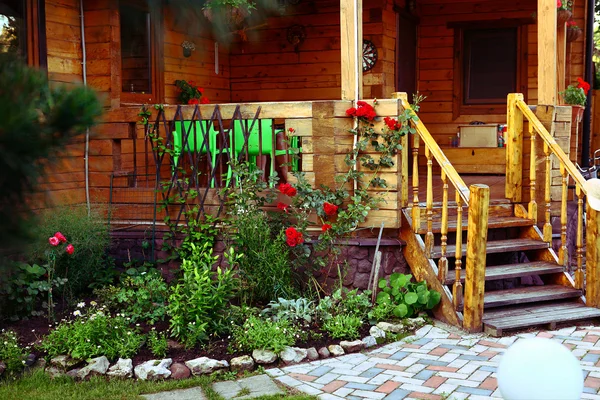 Houten huisje huis veranda en tegel pad in de bloeiende zomertuin — Stockfoto