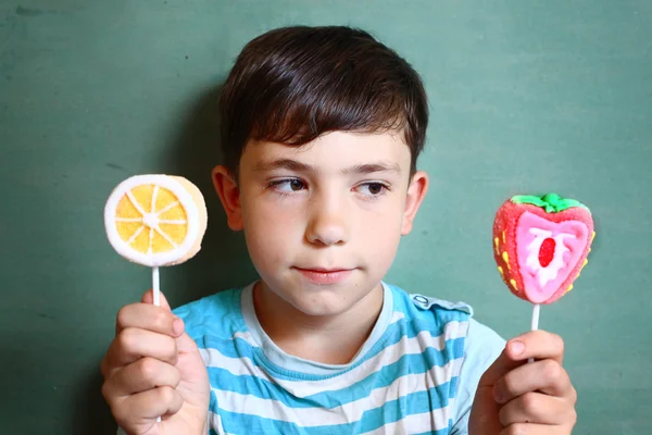 Préadolescent beau garçon avec deux bonbons moelleux sur bâton isolat — Photo