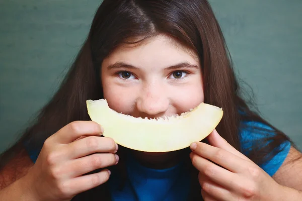 Preteen beautiful girl with long dark hair with slice of melon i — Stock Photo, Image