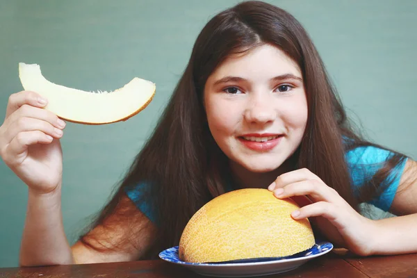 Preteen beautiful girl with long dark hair with slice of melon i — Stock Photo, Image