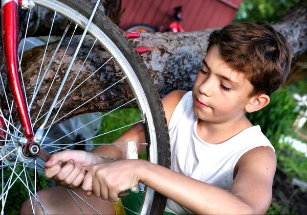 Ładny chłopak preteen zrobić rapairment z jego bisycle — Zdjęcie stockowe