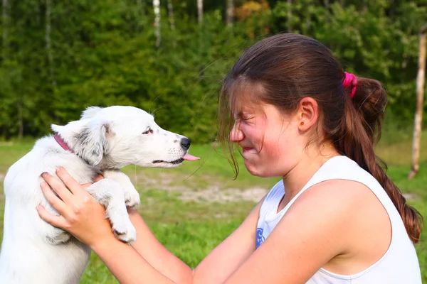 Witte pup lick tiener meisje op gezicht — Stockfoto