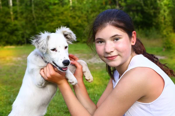 Meisje met witte pup op de zomer bos achtergrond spelen — Stockfoto