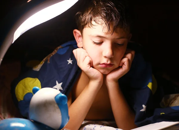 Preteen schöner Junge las Buch mit Lampe vor dem Schlafen — Stockfoto