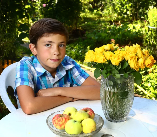 玫瑰盛开的花园背景上的男孩 — 图库照片