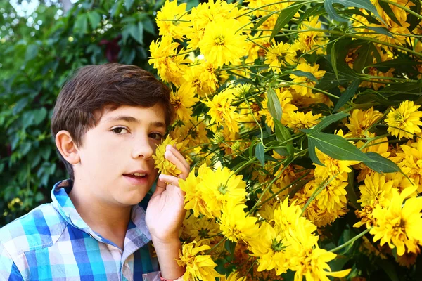 Preteen schöner Junge mit gelben großen Blumen Nahaufnahme Porträt — Stockfoto