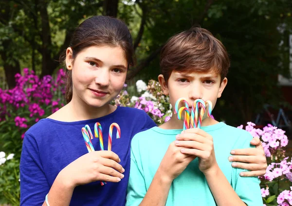 Adolescent fille et garçon avec rainbow candy sticks — Photo
