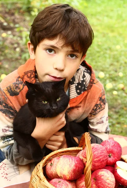 Menino com gato preto e maçãs vermelhas close up retrato — Fotografia de Stock