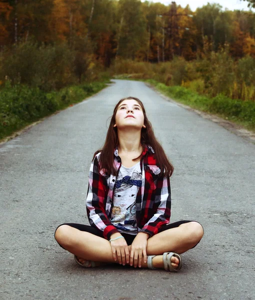 Beautiful teen girl sit on the country empty road — Stock Photo, Image