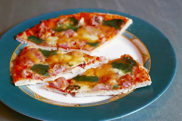 Pizzou nařezanou s pestem zelené sýrem na talíři — Stock fotografie