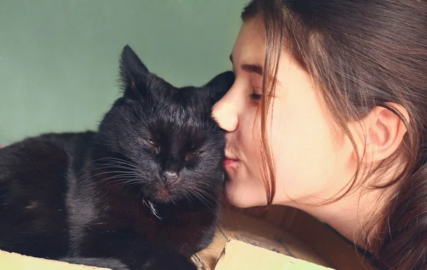Девушка-подросток целует черную кошку крупным планом — стоковое фото