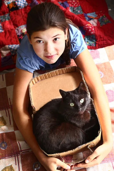 Meisje en zwarte kat in kartonnen doos kijken omhoog — Stockfoto
