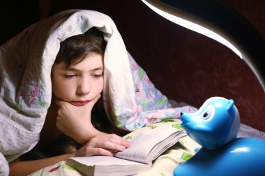 gece saat içinde battaniyenin altında kitap okuma çocuk