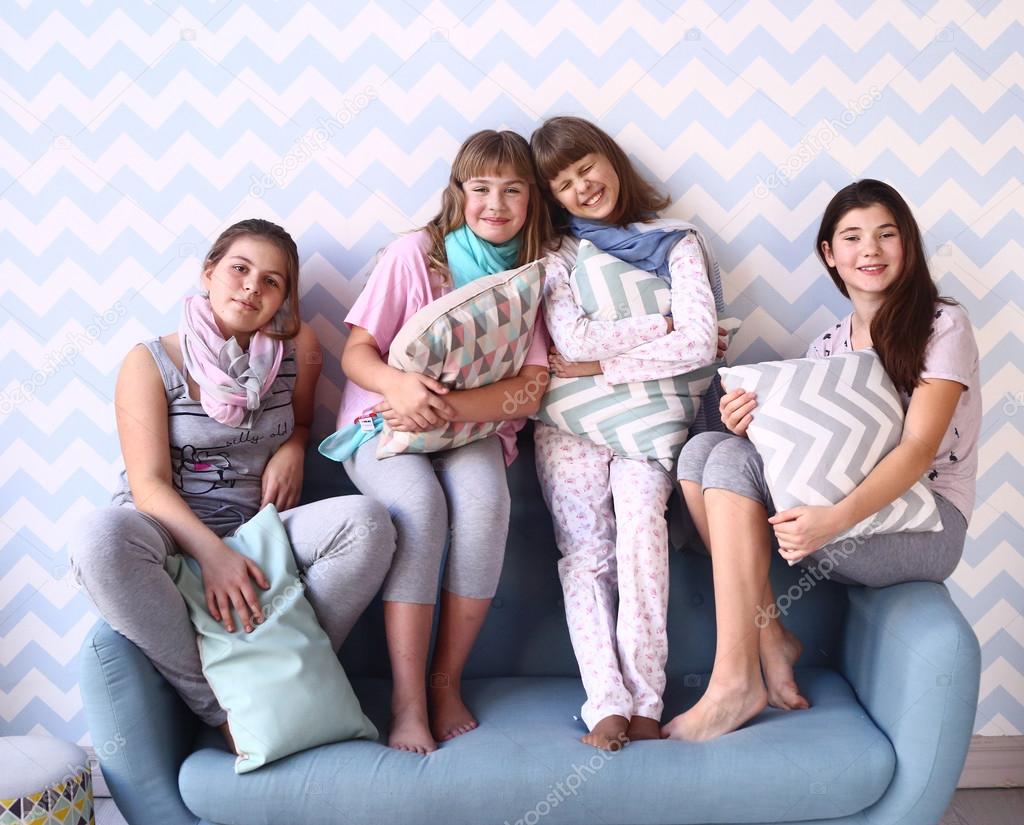 teen girls in pajamas with pillows on the sofa