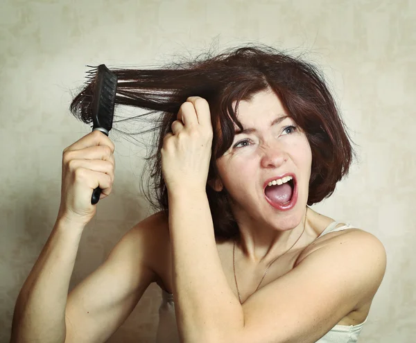 Жінка намагається розчісувати волосся — стокове фото