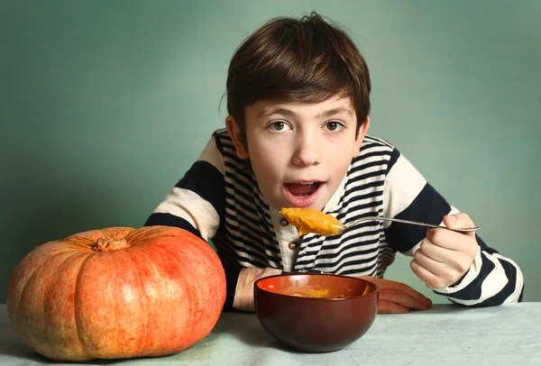 Jongen met grote oranje pompoen eten mash crème soep — Stockfoto