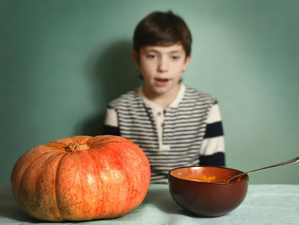 Jongen met grote oranje pompoen eten mash crème soep — Stockfoto