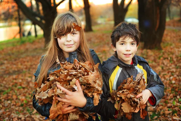 Menino e menina com folhas secas segurar pronto para jogar — Fotografia de Stock