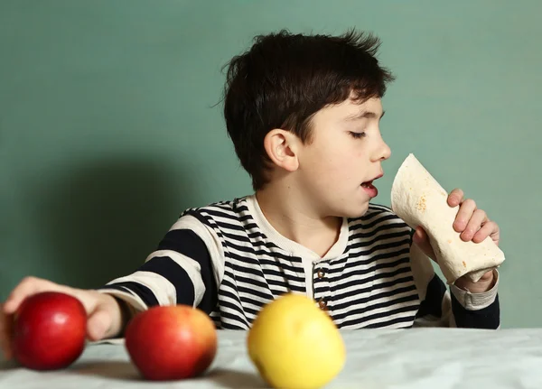 Menino comer fast food rolo recusar maçãs frescas — Fotografia de Stock