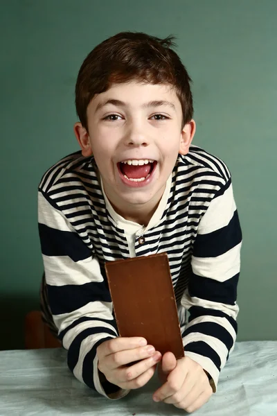 Menino pré-adolescente feliz com barra de chocolate — Fotografia de Stock