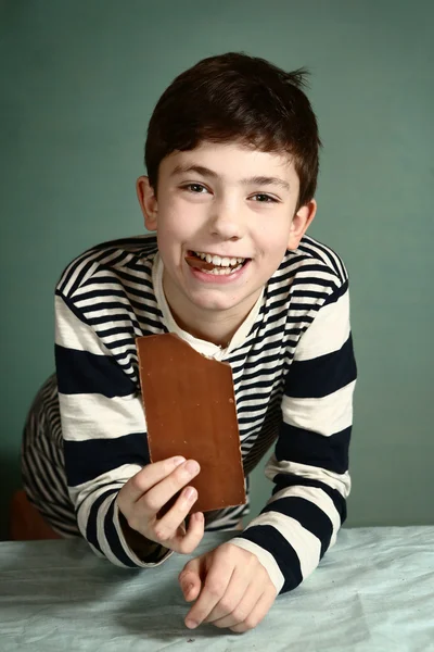 Menino pré-adolescente feliz com barra de chocolate — Fotografia de Stock