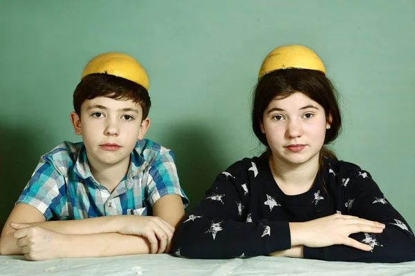 Enfants frères et sœurs épluchage de pamplemousse faire chapeau drôle — Photo