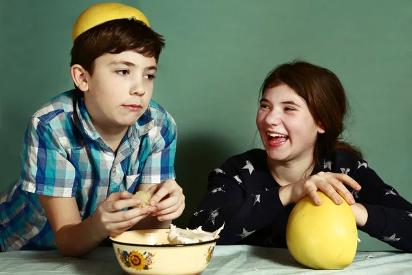 Kinderen broers en zussen peeling grape fruit maken grappige hoed — Stockfoto