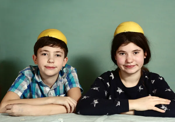 Enfants frères et sœurs épluchage de pamplemousse faire chapeau drôle — Photo