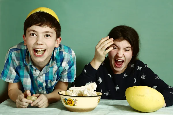 Kinderen broers en zussen peeling grape fruit maken grappige hoed — Stockfoto