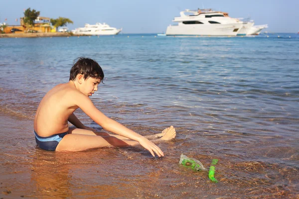 Menino na praia tomar banho de sol brincar com areia — Fotografia de Stock