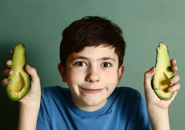 Söt preteen pojke håller avokado halva i hand — Stockfoto