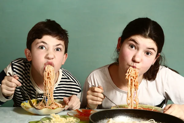 Happy teen siblings boy and girl eat spaghetti — Stock Photo, Image