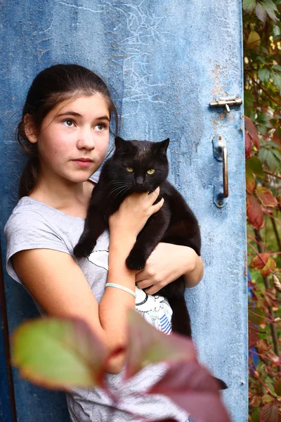 Симпатичная девочка-подросток с черной кошкой — стоковое фото