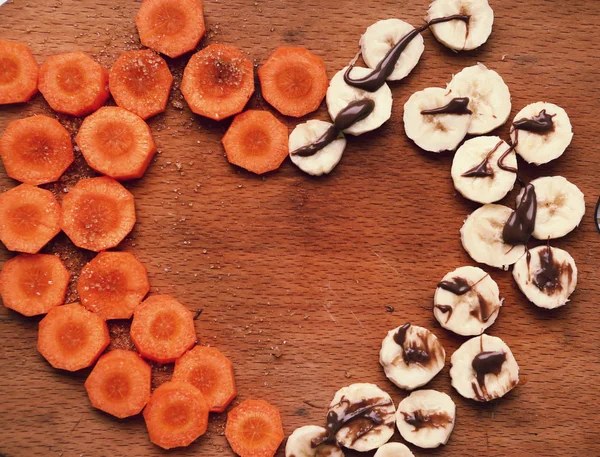 Gesneden wortel en banaan cirkels vormen hart — Stockfoto