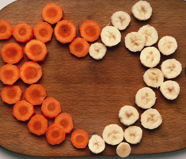 Vágott sárgarépa és banán kört alkotó szív — Stock Fotó