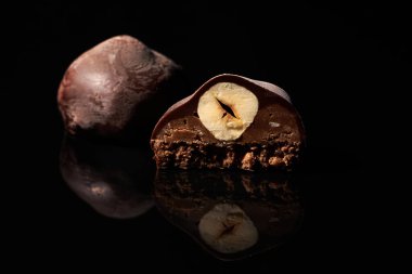 Siyah arka planda fındıklı çikolatalı şekerin tamamı yansımalı.