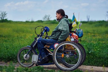 Tekerlekli sandalyedeki genç adam yolda gidiyor.