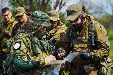 Rus asker üniformalı bir grup hava yumuşaklığı oyuncusu bir harita izliyor.