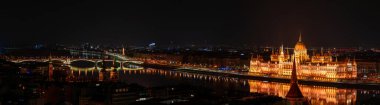 Gece Budapeşte, Parlamento, şehrin arka planına karşı nehirdeki ışıkların yansıması, şehrin manzarası.
