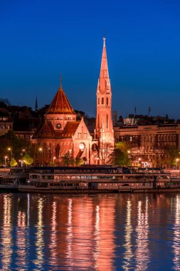 Budapeşte geceleri, Tuna 'nın kıyısındaki kilise, sudaki gece ışıklarının yansıması, şehir manzarası.