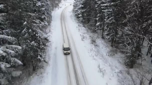 Vista de olhos de pássaros de carro dirigindo na estrada de gelo nevado explorando paisagens locais no inverno, vista de olhos de pássaros de carro de automóvel em movimento na área cercada por bela floresta de coníferas. — Vídeo de Stock